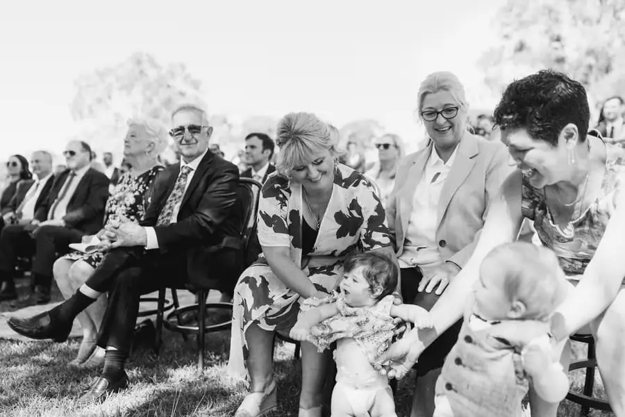 Black and white photograph of seated guests smiling with small children