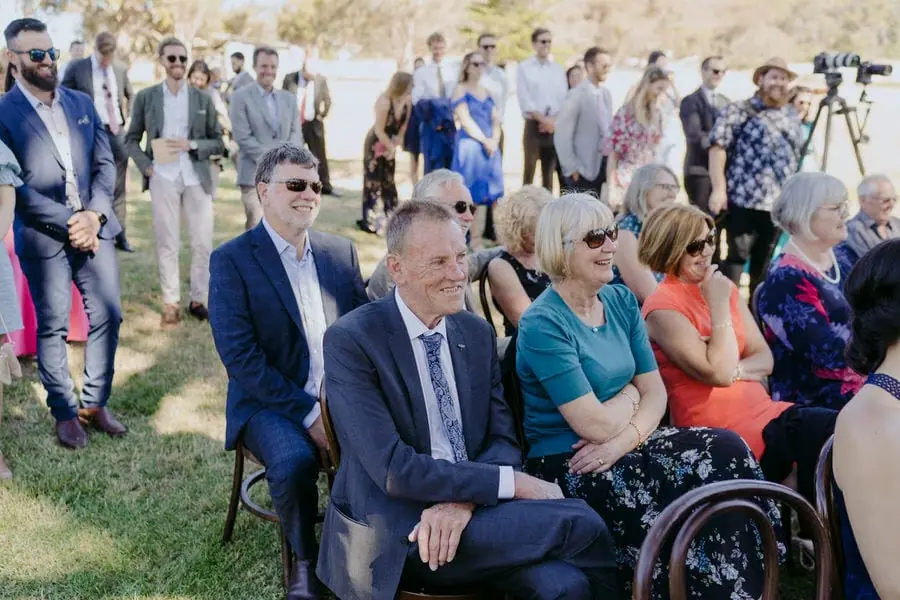 Guests smiling while seated in the front rows of the ceremony