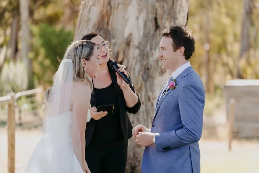 Bride leaning toward the groom beside the celebrant during the ceremony