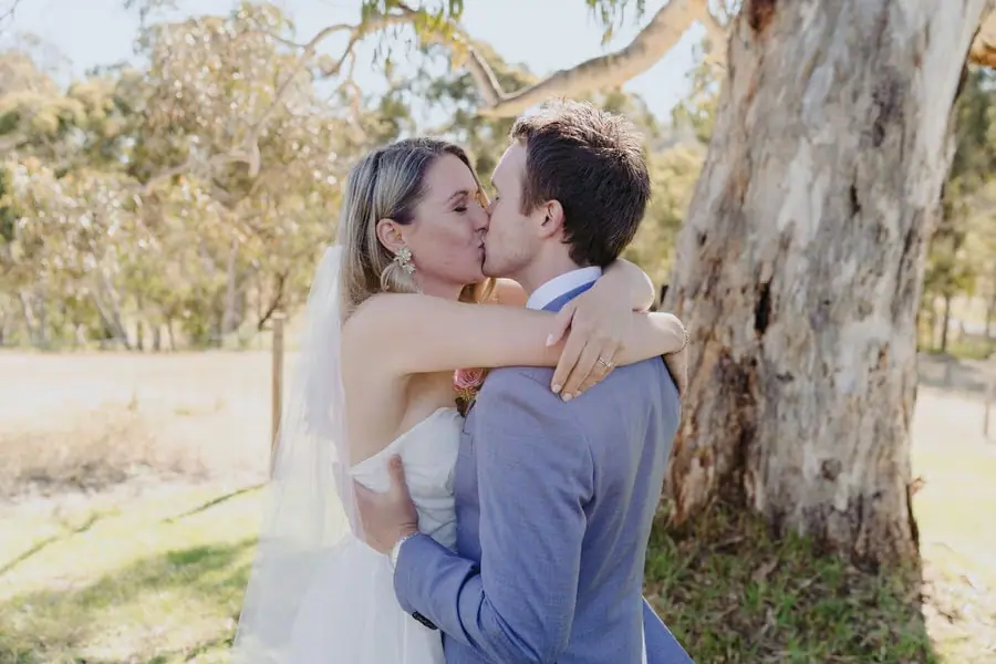 Bride and groom kissing beneath a large tree