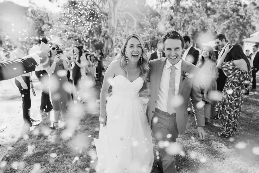 Black and white photograph of the couple laughing through falling confetti