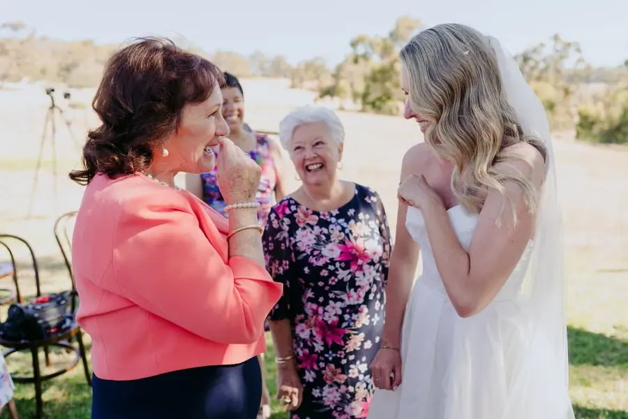 Bride laughing with two women after the outdoor ceremony