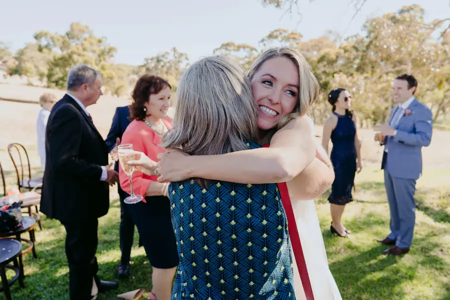 Bride hugging a guest while smiling toward the camera