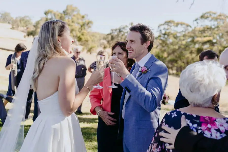Bride and groom raising glasses together with guests outdoors