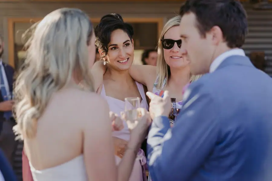 Bride and groom chatting with guests over drinks outside