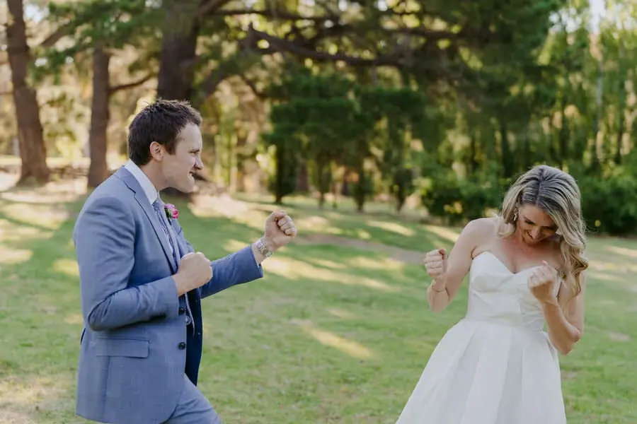 Bride and groom laughing and gesturing toward each other on a lawn