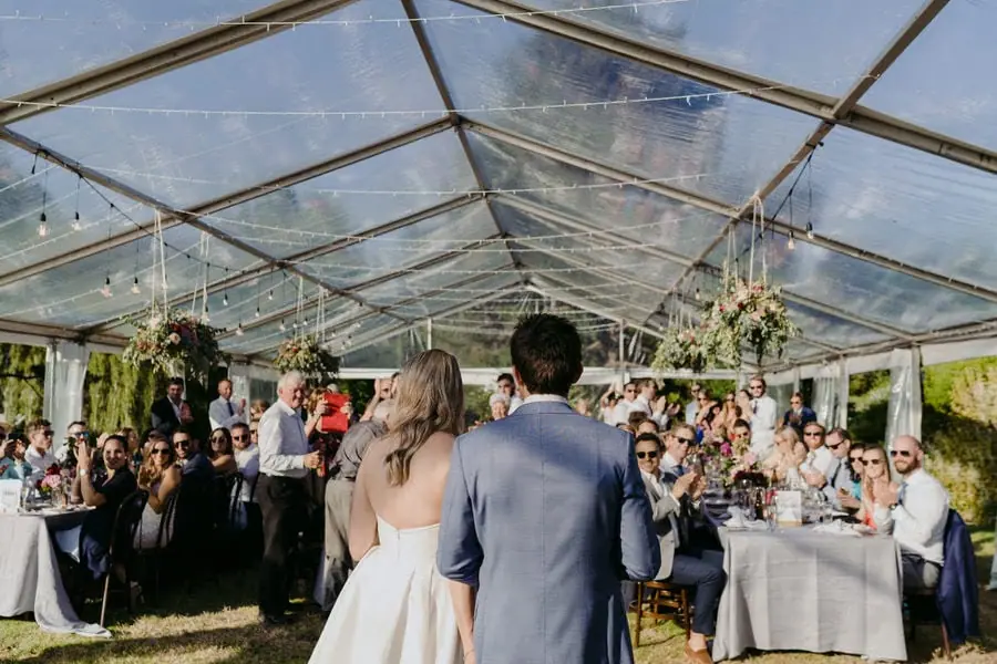 Bride and groom entering the reception marquee as guests applaud