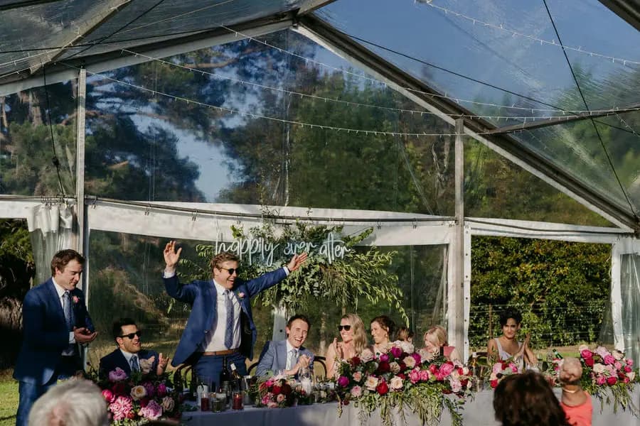 Wedding party cheering at the flower-decorated reception table