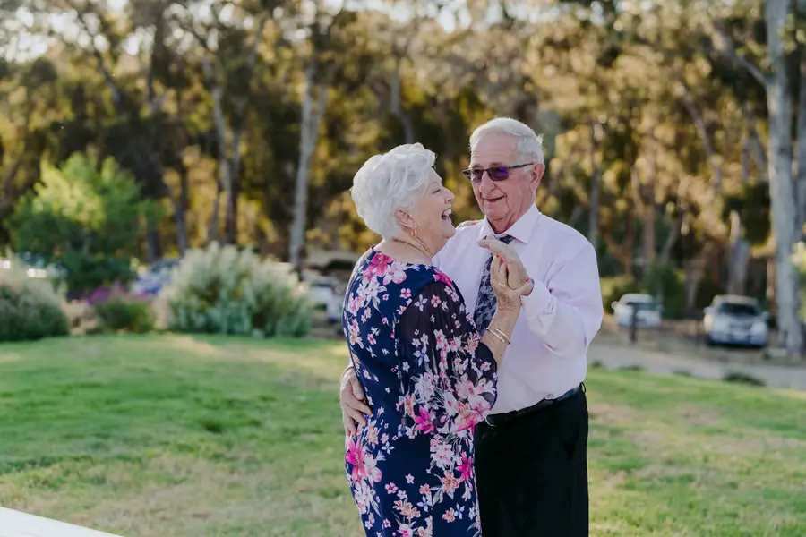 Grey-haired couple dancing together on the lawn