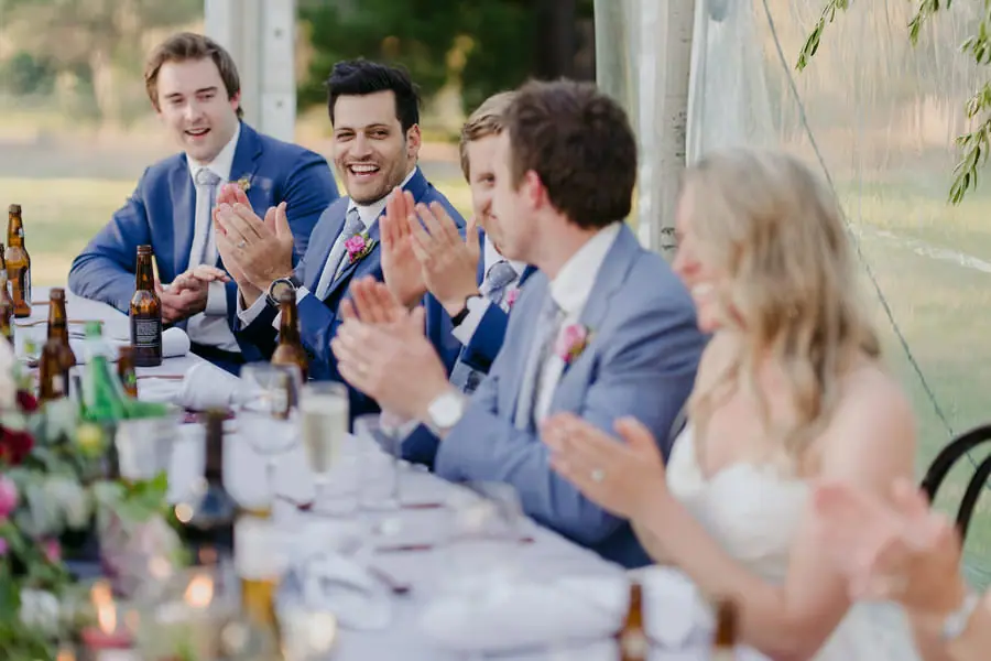 Wedding party smiling and applauding at the reception table