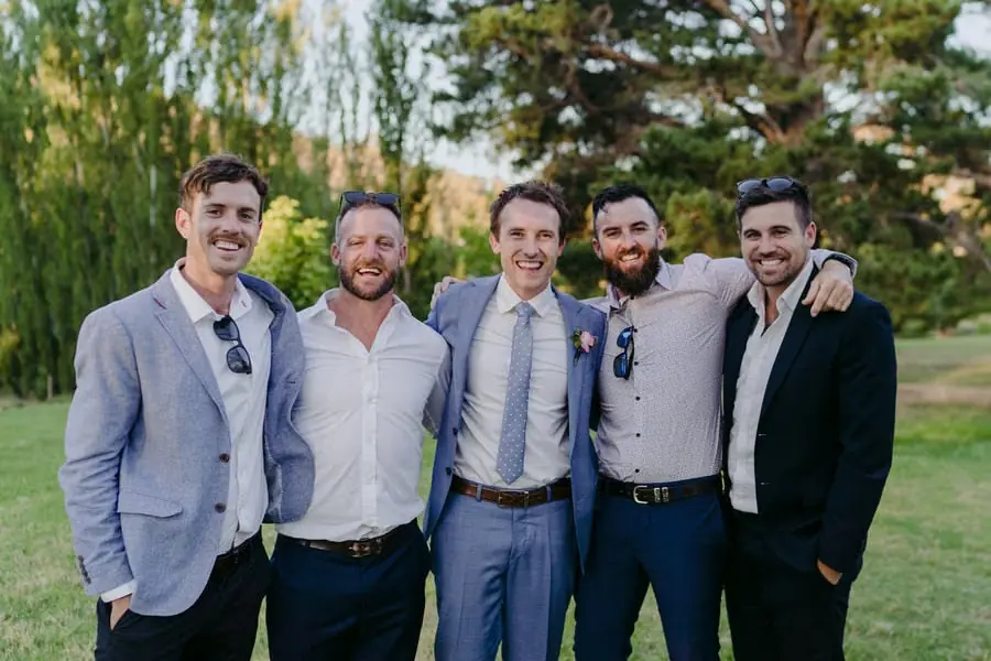 Groom posing with four smiling guests outdoors