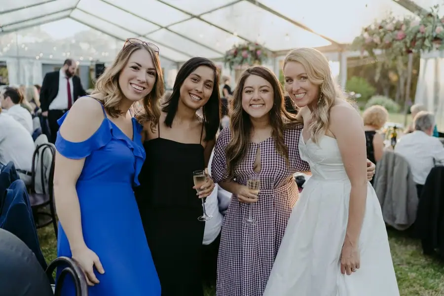Bride smiling with three guests inside the reception marquee