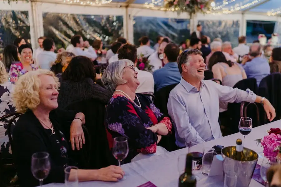 Seated guests laughing together beneath the marquee lights