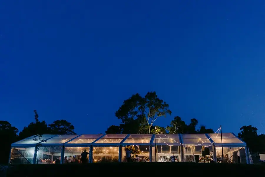 Illuminated reception marquee beneath a deep blue evening sky