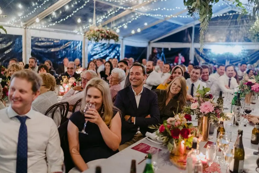 Guests laughing together at flower-decorated reception tables after dark