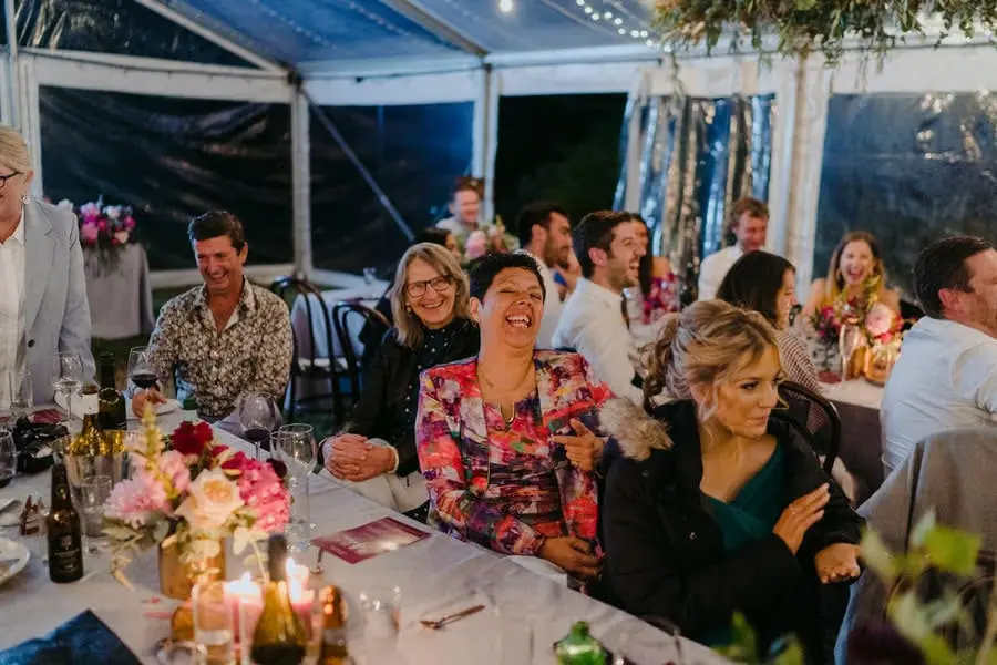 Seated guests smiling and laughing during the evening reception