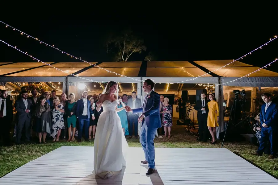 Bride and groom dancing on an outdoor dance floor with guests watching