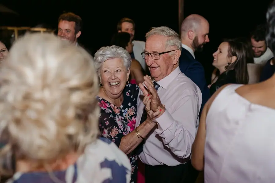 Grey-haired couple laughing together among guests on the dance floor