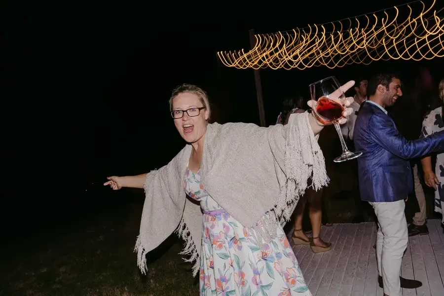 Guest dancing with her arms spread while holding a wine glass