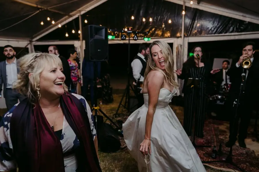 Bride smiling while dancing beside a guest and the live band
