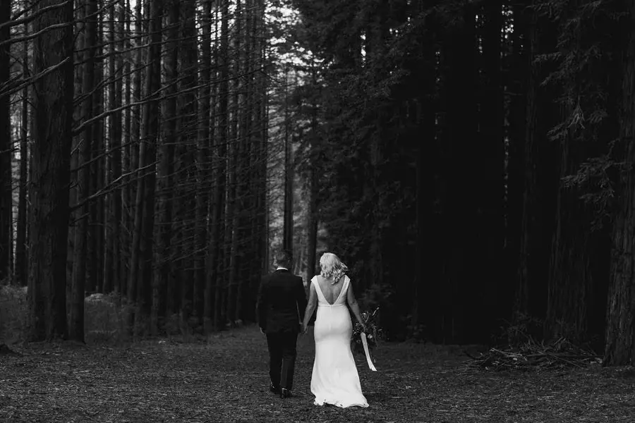 Black and white photograph of the couple walking away along a forest path.