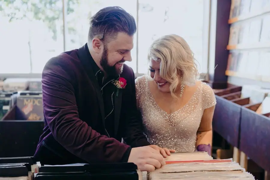 Couple smiles while signing wedding paperwork indoors.