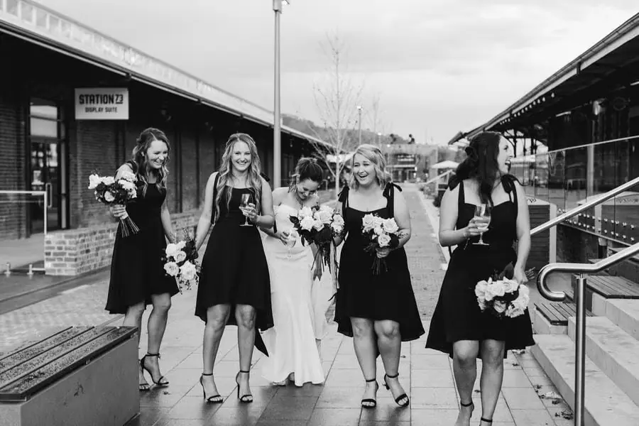 Black and white photograph of the bride walking with bridesmaids along a station platform.