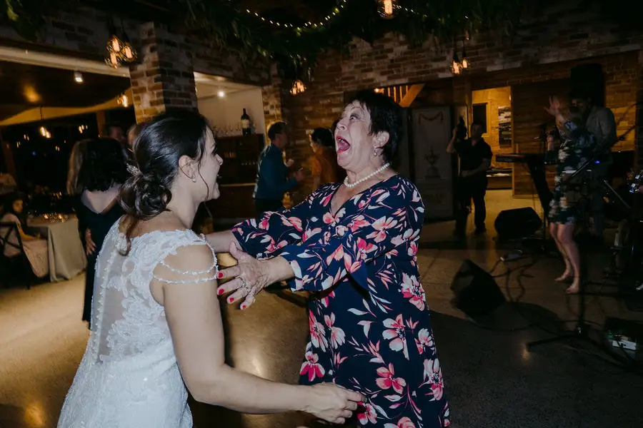 Bride and an older woman laugh together on the dance floor.