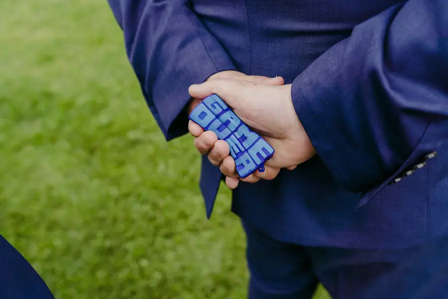 Close view of a man holding a blue game controller behind his back.