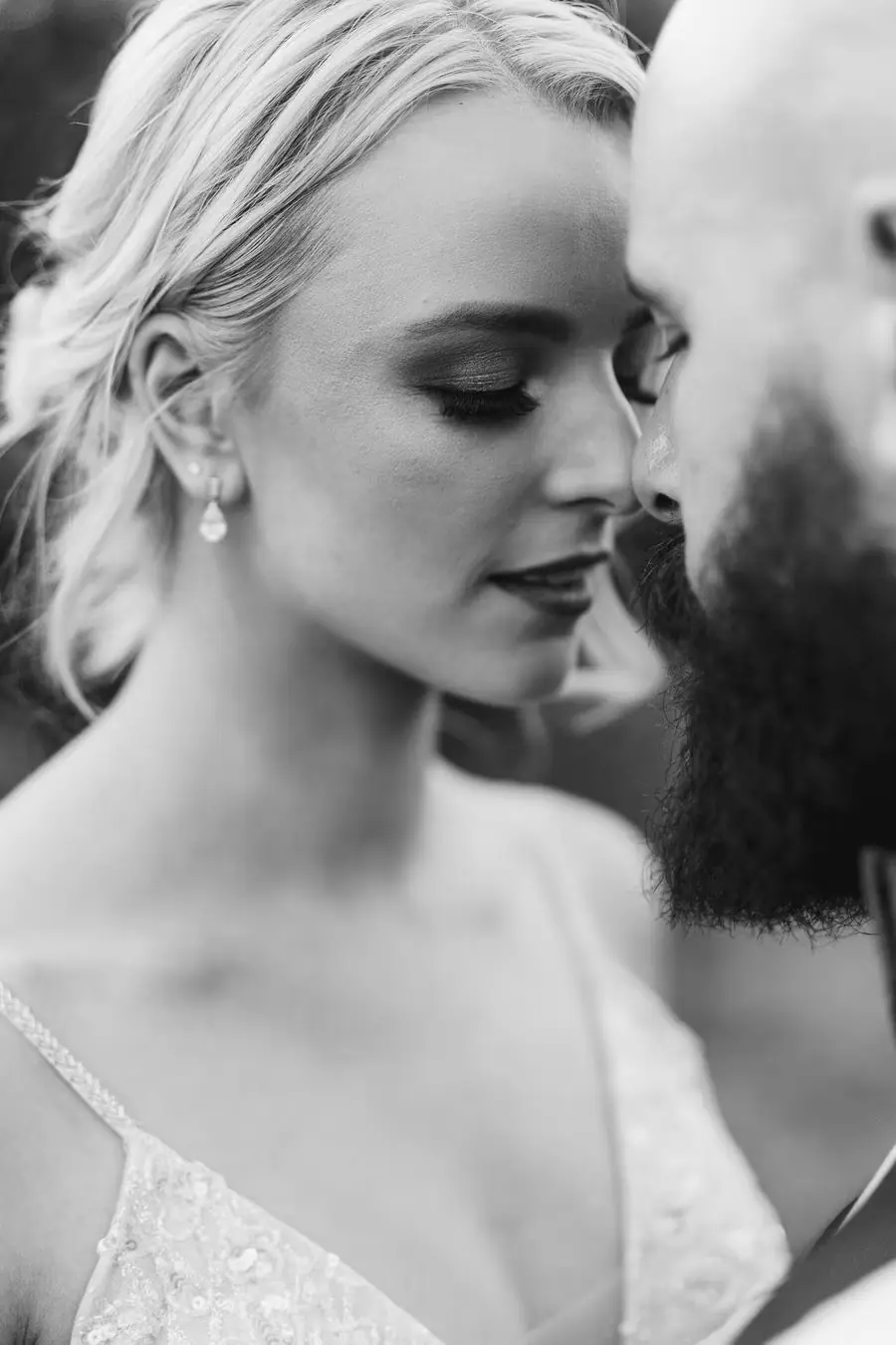 Black and white close portrait of the bride looking toward the groom.