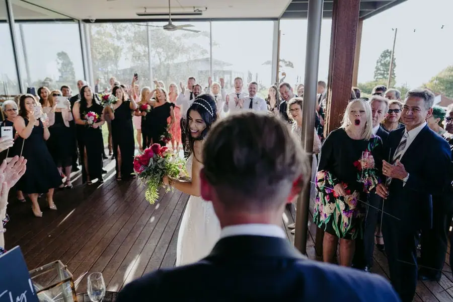 Guests applaud the couple inside a bright reception room.