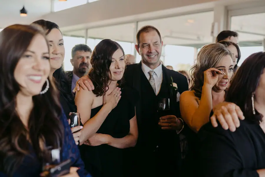 Guests smile and embrace together indoors.