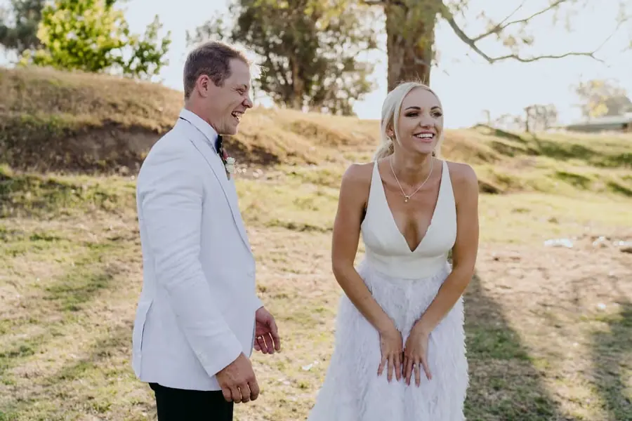 Couple laughs together on a sunlit path.
