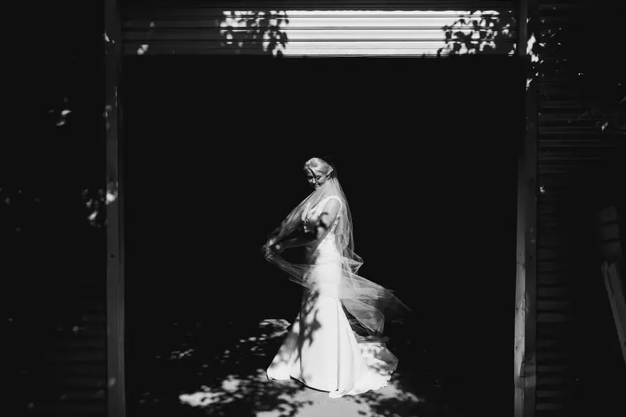 Black and white portrait of the bride in bright light against a dark doorway.