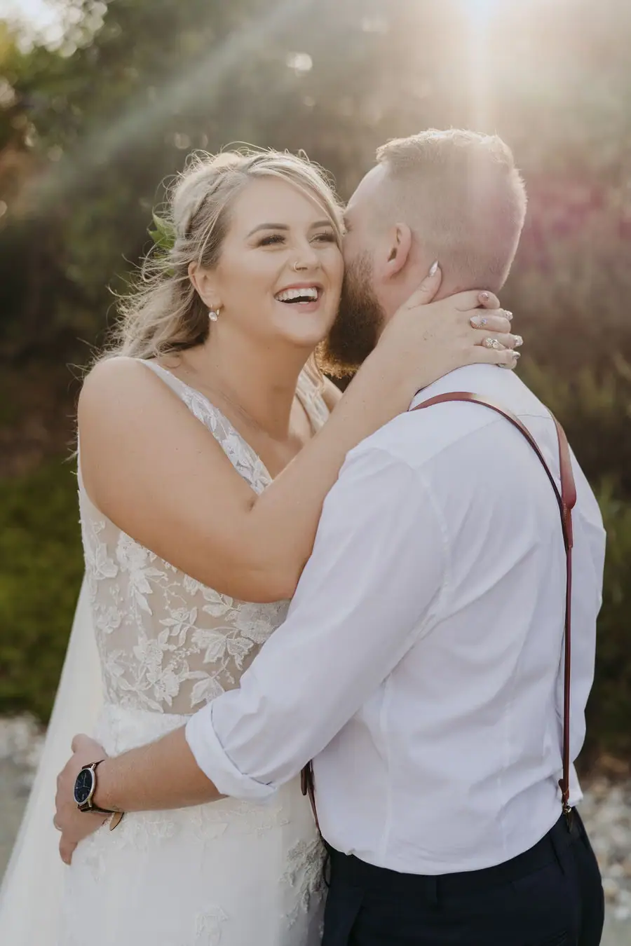 Couple embraces and laughs together in warm sunlight.