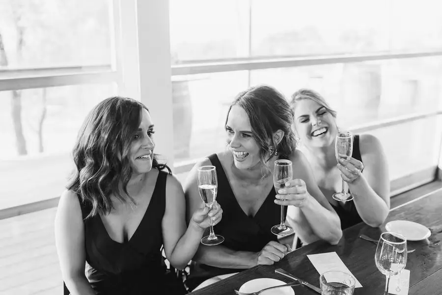 Black and white photograph of women laughing together with champagne glasses.