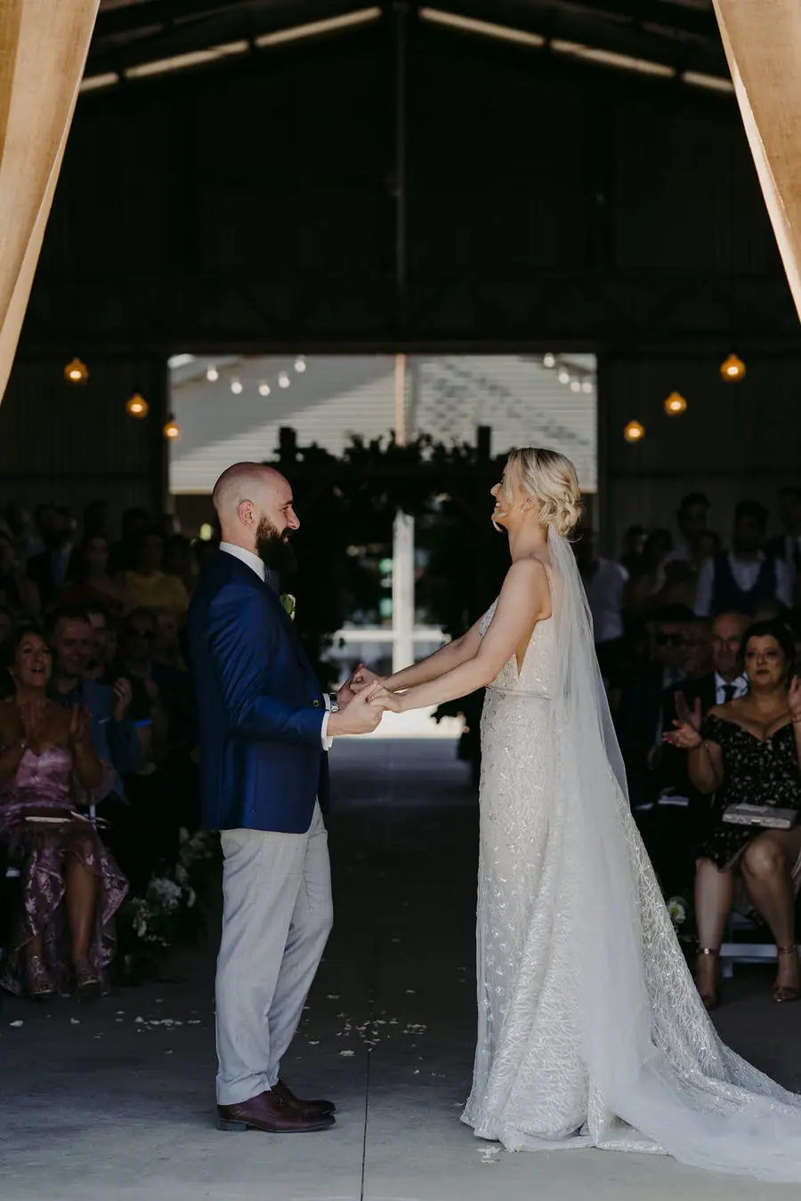 Couple dances together in a reception doorway with guests watching.