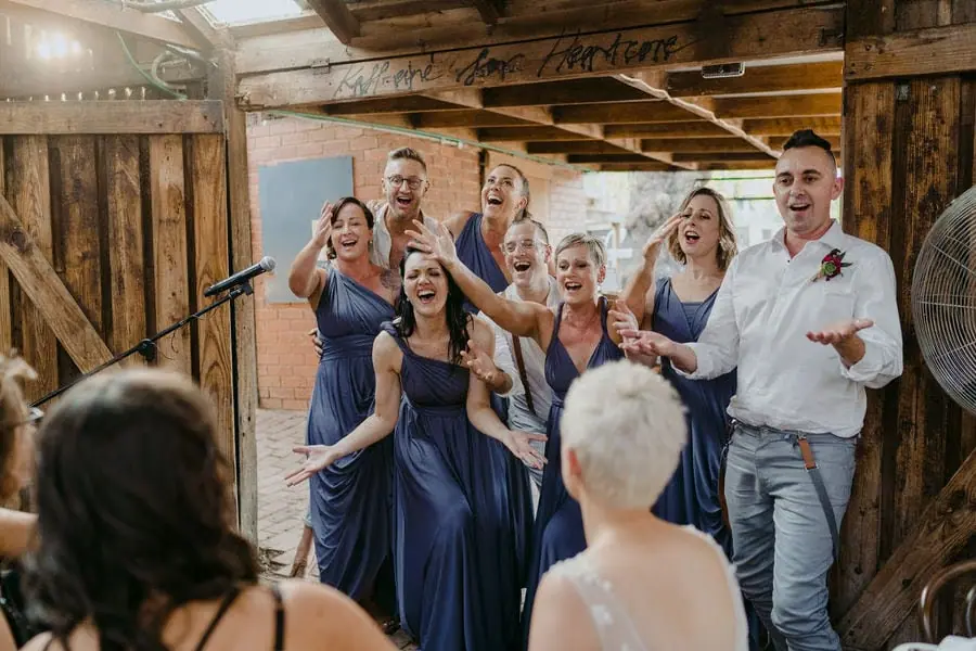 Guests sing and celebrate together beside a microphone inside a wooden venue.