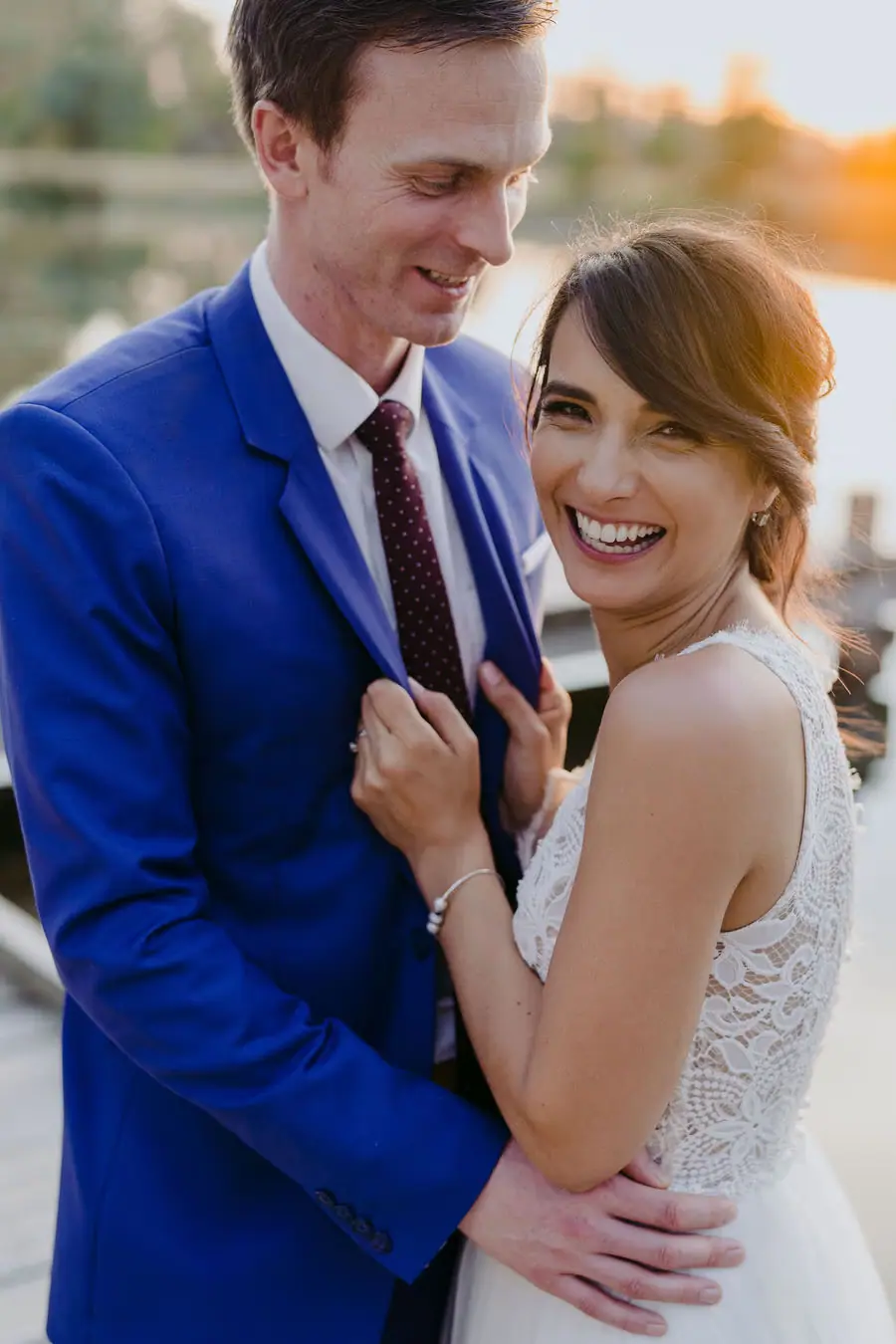 Bride smiles toward the camera while embracing the groom.