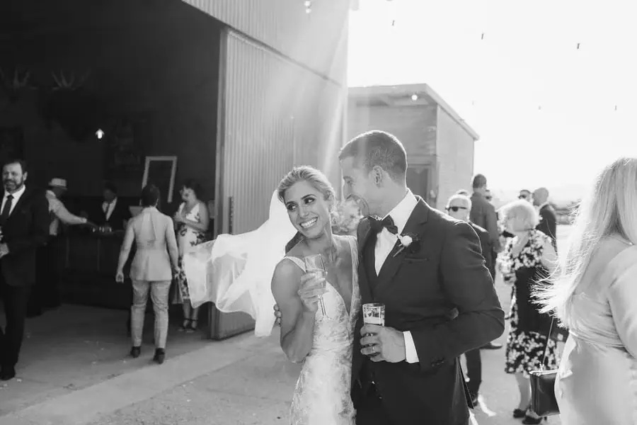 Black and white photograph of the couple smiling together outside the reception building.