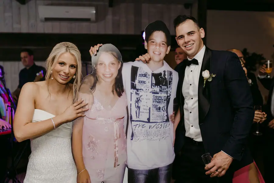 Couple poses with cardboard cut-outs of two people at the reception.