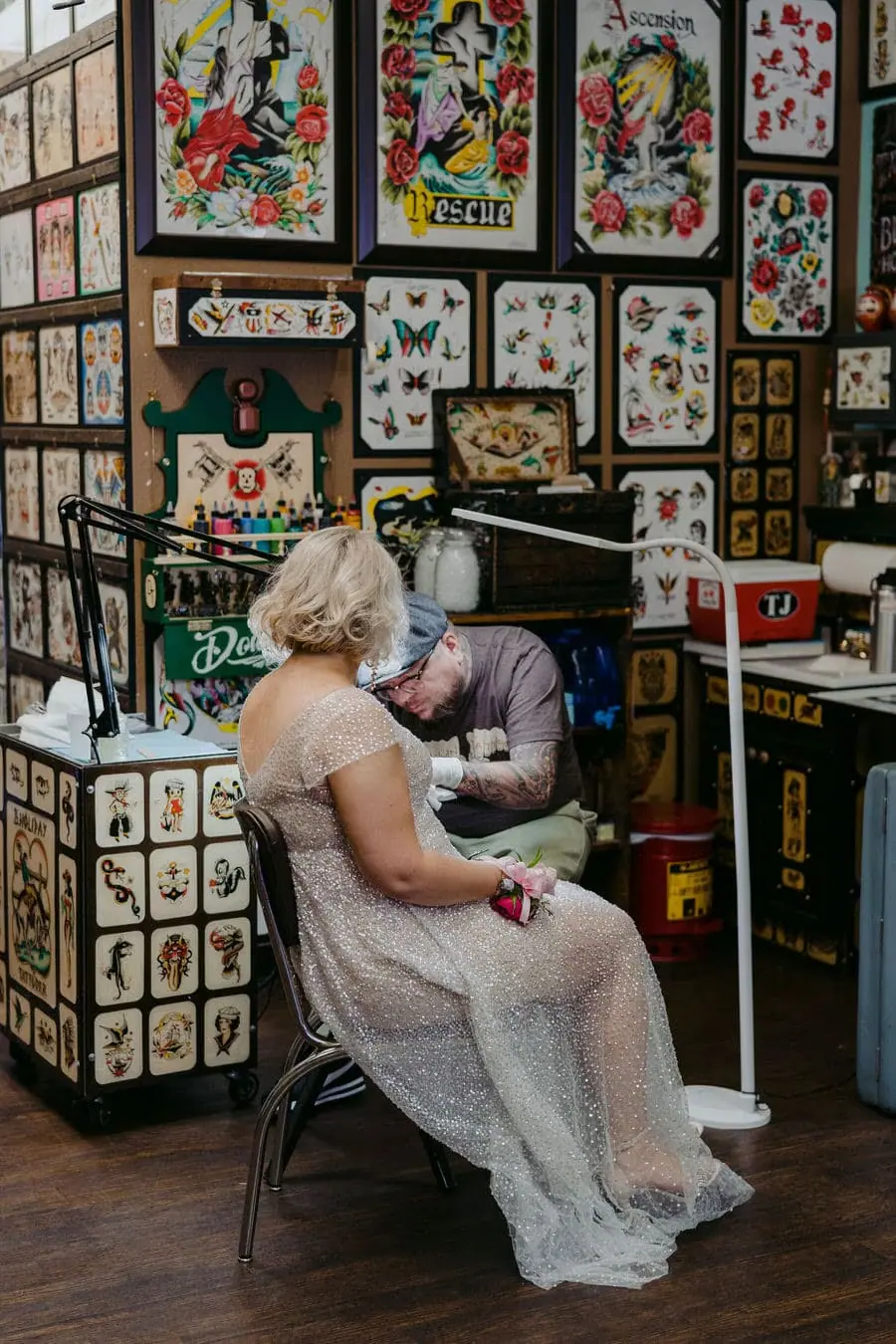 Bride sits beside the groom in a shop surrounded by framed artwork.