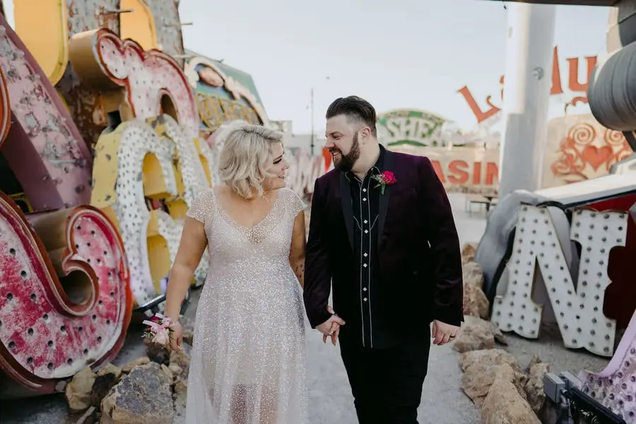 Couple walks hand in hand among colourful vintage signs.
