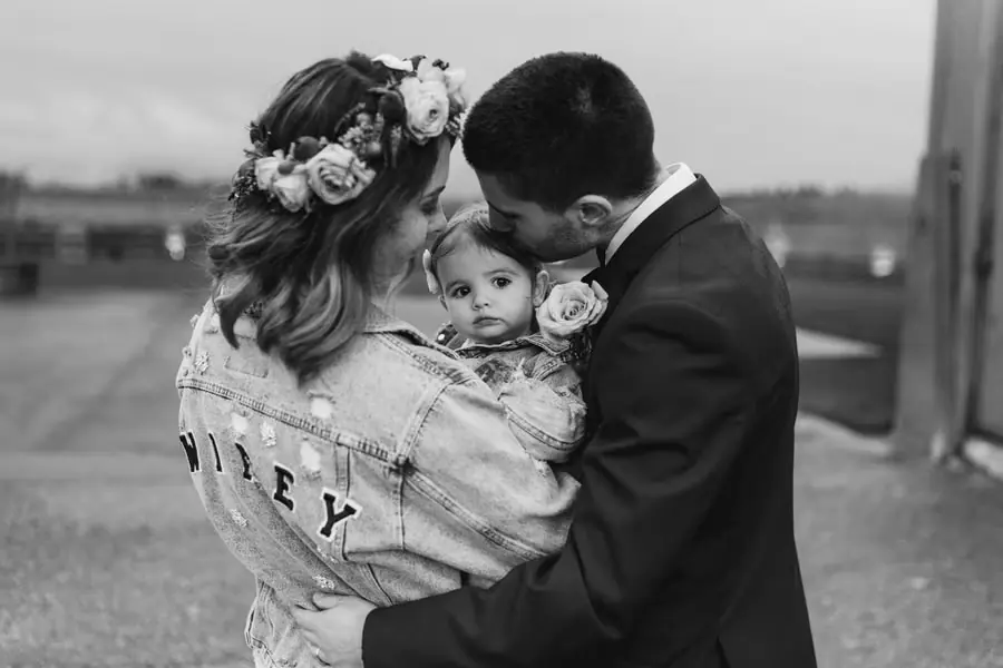 Black and white photograph of the couple embracing a small child outdoors.