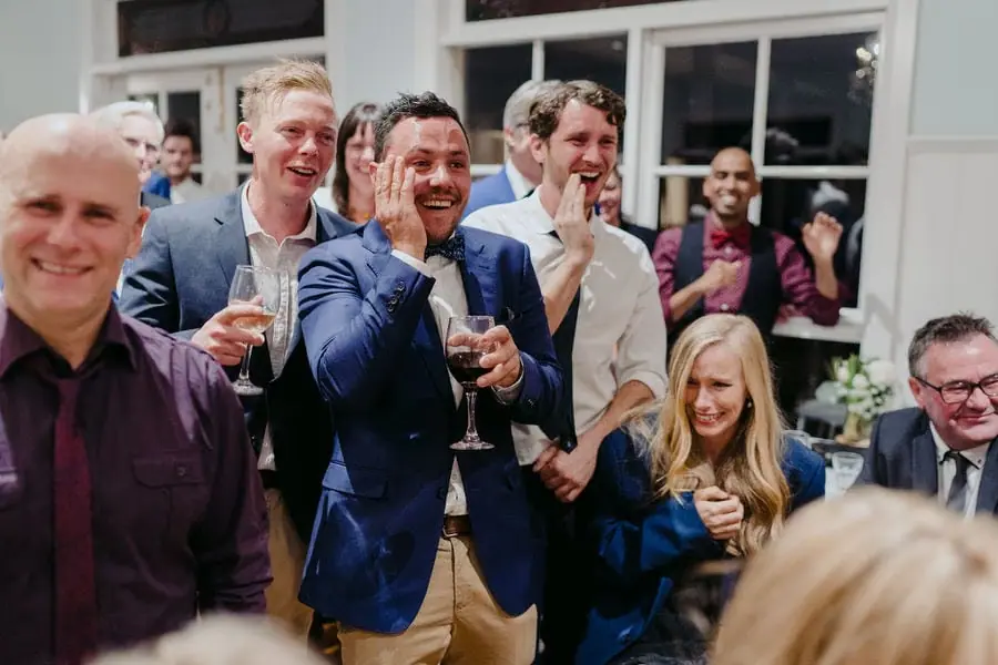 Guests smile and applaud together with drinks in their hands.