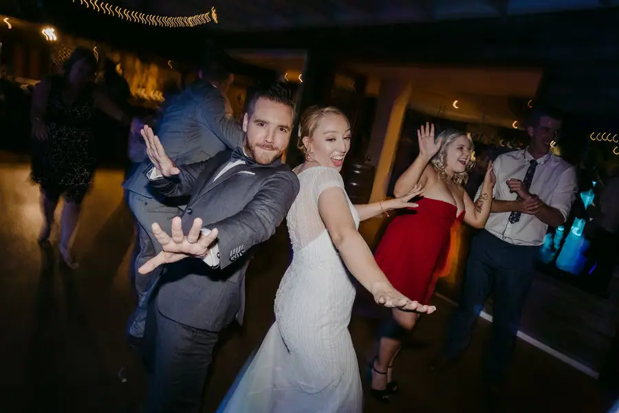 Couple dances back to back with their hands outstretched at the reception.