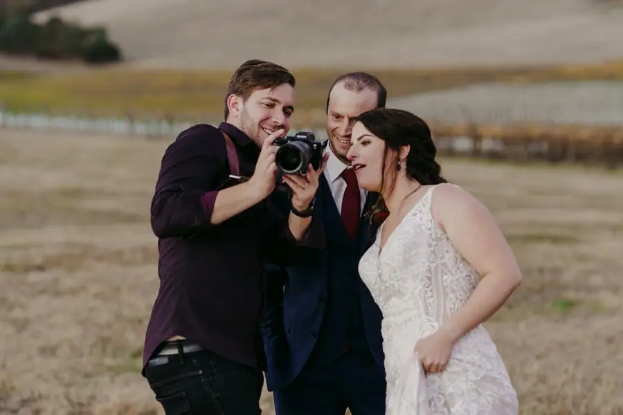 Couple reacts to a photograph on a camera held by the photographer.