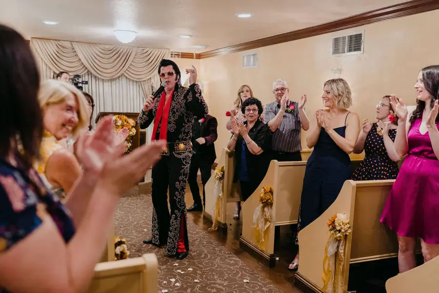 Elvis-style performer entertains applauding guests in a chapel.