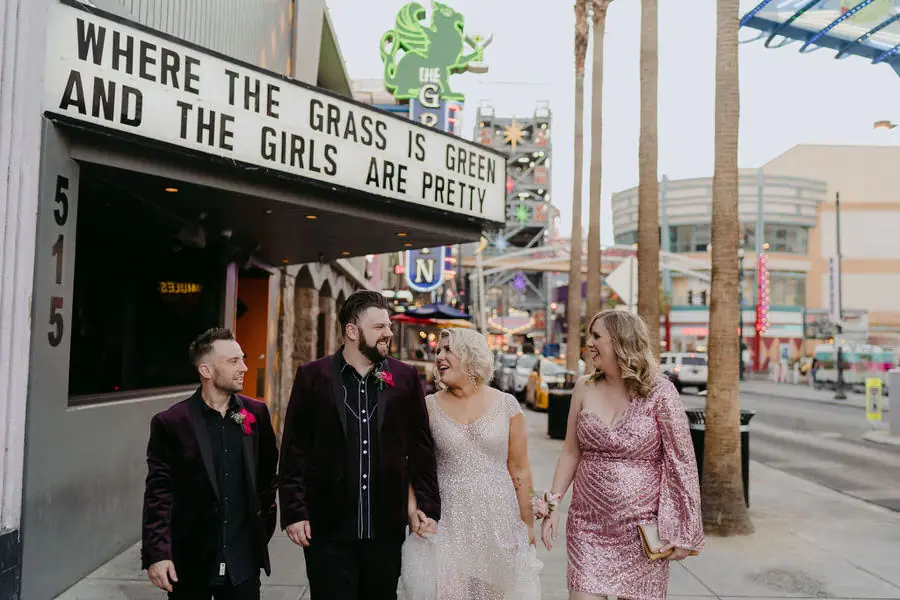 Couple and guests walk together beneath a city theatre sign.