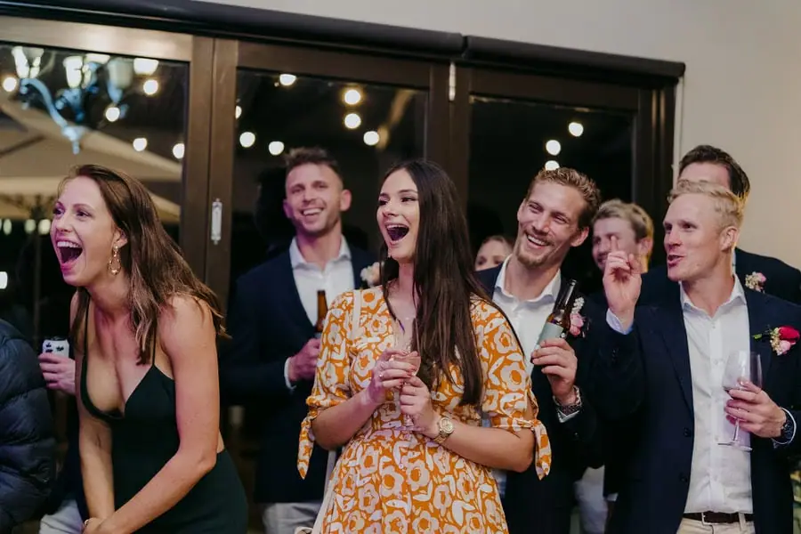 Guests laugh and react while holding drinks at the reception.